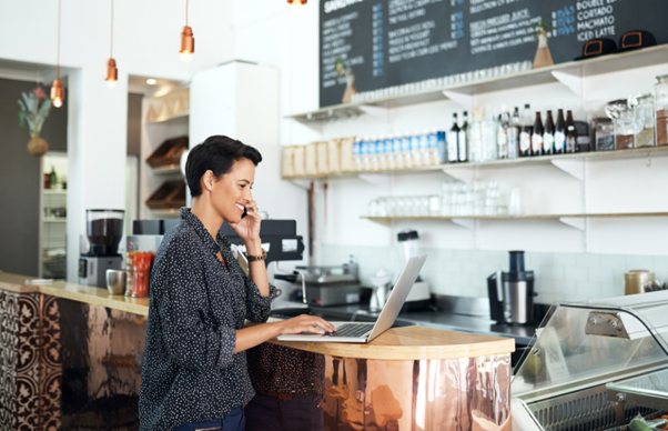 Small business owner working in a café representing a local marketing strategy to attract customers and build brand awareness.